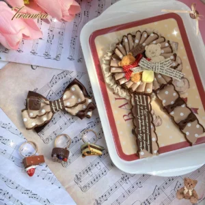 Teddy bear lolita brooch with polka-dot satin ribbon and dessert-themed accessories flat lay styled with vintage sheet music and pink tulips
