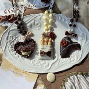Set of three dessert themed lolita necklaces overhead shot white embossed ceramic plate vintage lolita background cloth delicate resin pendants tiny fabric bows