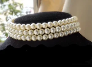 Three-layer white pearl tiered choker necklace displayed on black velvet jewelry neck mannequin, showing graduated pearl strand design with silver clasp and extension chain
