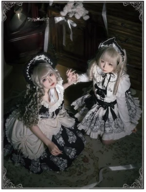 Twin maid-style lolita OP dresses with two-tone color matching and ruffled skirt hems - side view of curly blonde models kneeling in dark wooden vintage room showcasing classic lolita silhouette