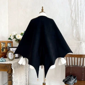 Back view of vampire Ouji Lolita bat cape outfit displaying dramatic bat-wing silhouette solid black fabric and gold tassel pendants at cape hem