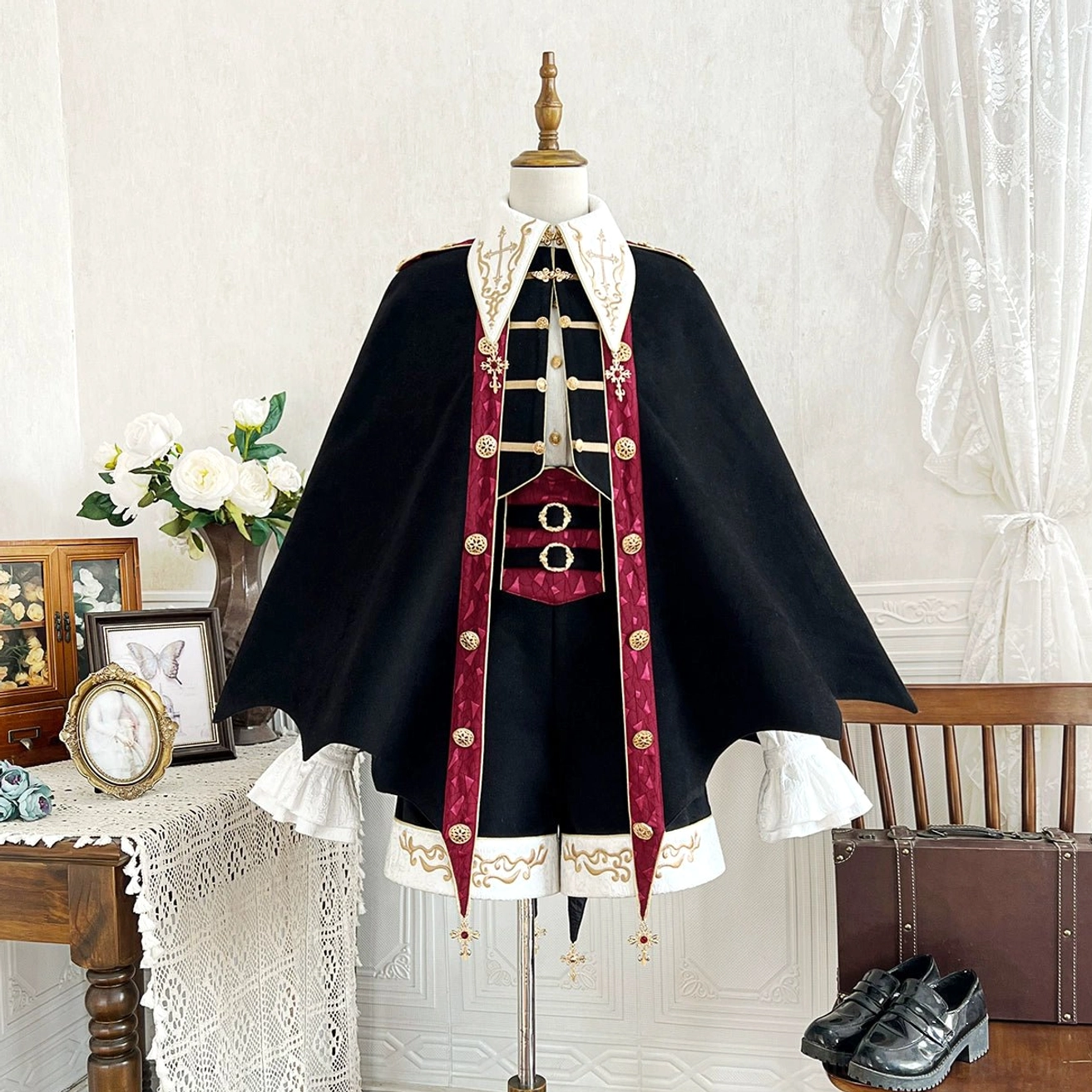 Vampire Ouji Lolita bat-shaped cape three-piece set front view on dress form showing black jacket with burgundy trim gold embroidery ruffled shirt and decorative shorts