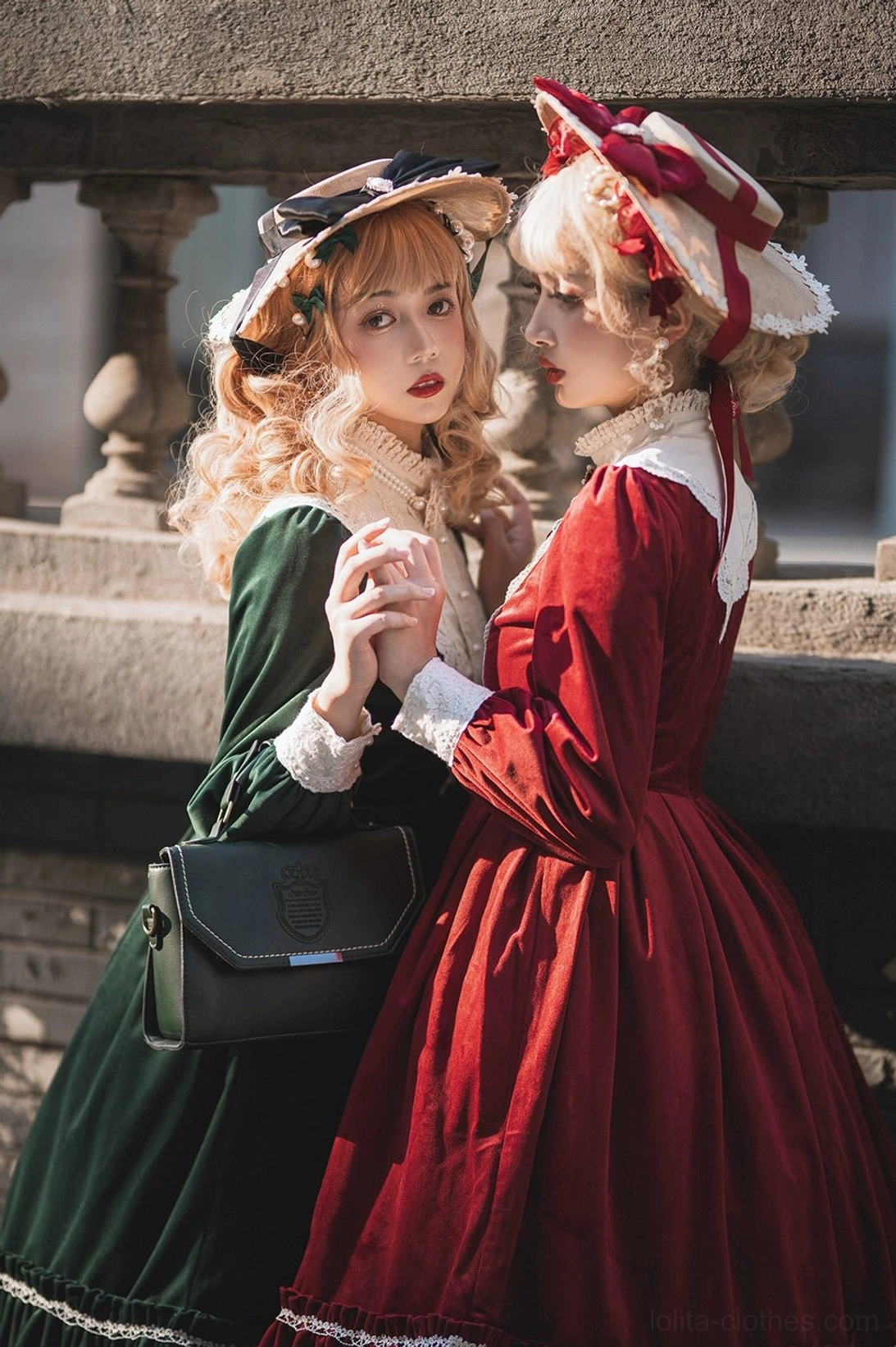 Vintage velvet lolita one-piece dress close-up side front group shot stone balcony railing two models holding hands matching retro lolita hats leather crossbody bags