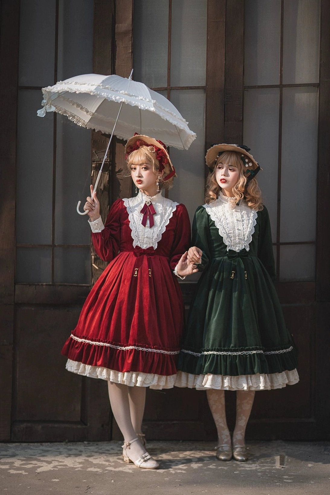 Vintage velvet lolita OP dress front full-body group shot indoor vintage wooden doorway two standing female models white lace parasol coordinated retro curly hairstyles