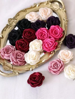 Top-down view of assorted fabric rose hair accessories on vintage golden oval tray showing handcrafted realistic rose petal details