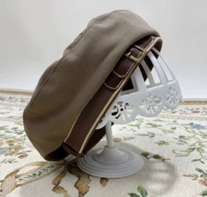 Vintage khaki Lolita beret hat with golden lace trim and metal buckle decoration displayed on ornate white stand
