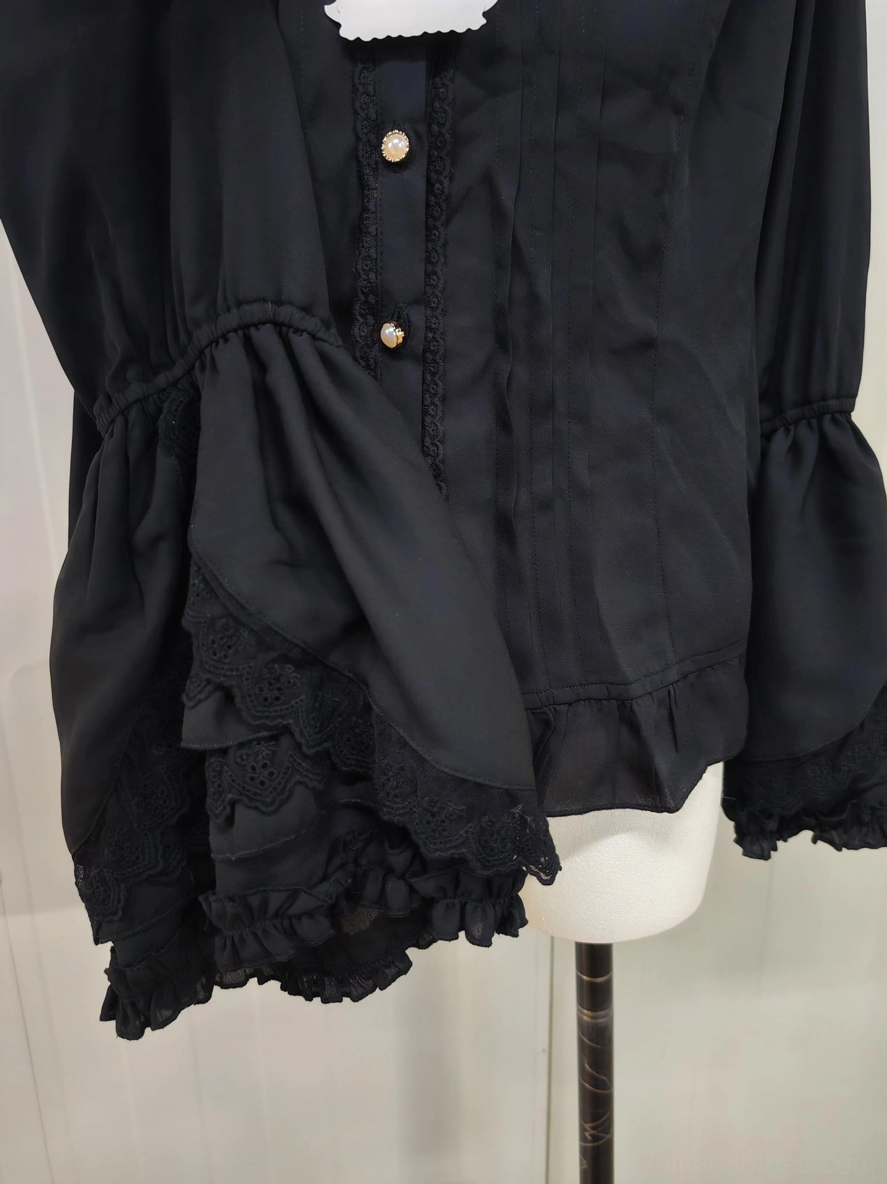 Black vintage lolita blouse side three-quarter view showing tiered lace ruffled flared sleeves gold-toned front buttons relaxed slim silhouette