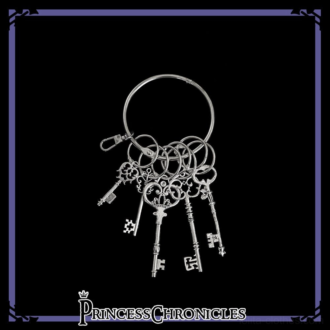 Vintage silver skeleton key ring charm with five intricately hollowed retro keys, polished alloy finish, featuring sturdy lobster clasp and spring key ring mechanism for secure Lolita bag attachment - flat lay product photography