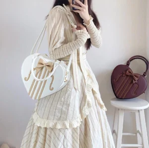 White and dark purple violin heart lolita bags with bowknot decoration and f-hole stripe pattern shown on model in beige striped lolita dress mirror selfie back view