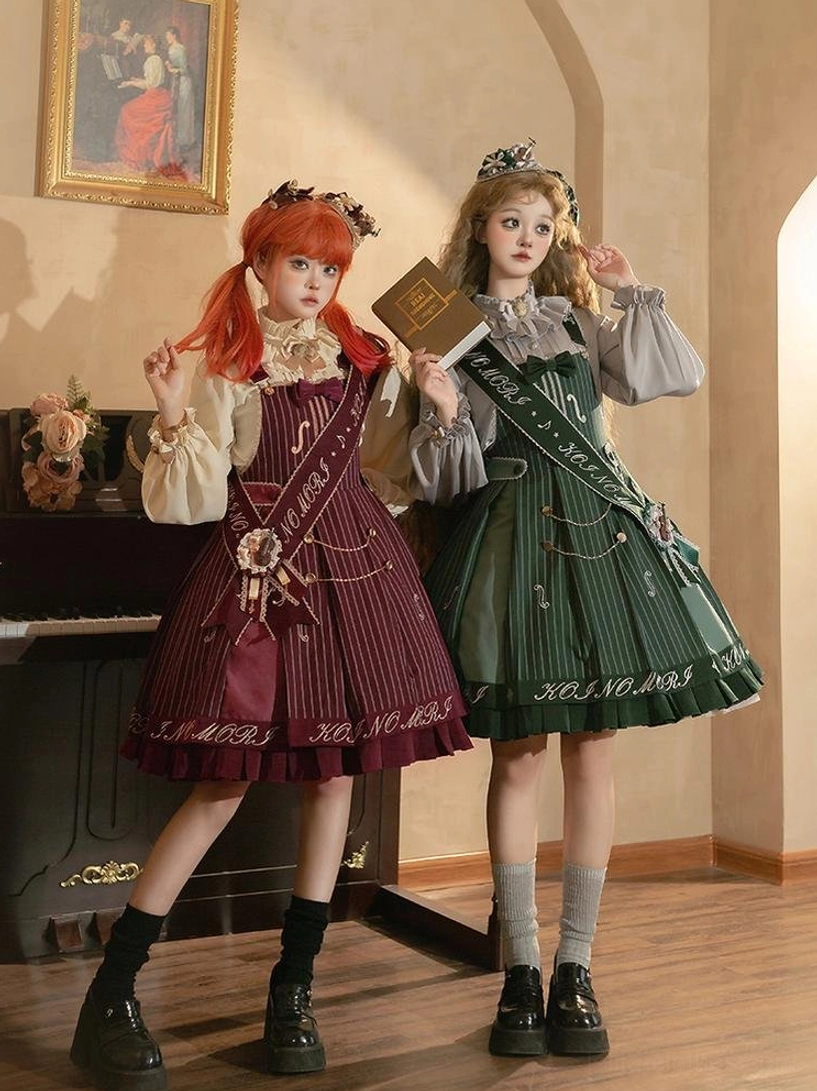 Two female models wearing wine red and navy blue violin preppy Lolita salopette sets with coordinating blouses and accessories in vintage piano studio setting front full body group shot