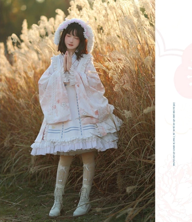 Kimono Lolita OP dress with white base, pink floral print and blue stripe apron overlay in prayer pose, three-quarter side view with ruffled skirt hem, furry hood, white lace boots and patterned sheer stockings