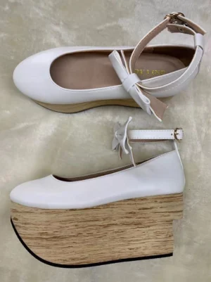 White ultrafine fiber leather wa lolita platform Mary Jane shoes featuring round toe, ankle strap with small decorative satin bow, smooth leather upper, thick simulated wood-grain wedge platform heel shown in frontal flat lay and side profile on light plush fabric background