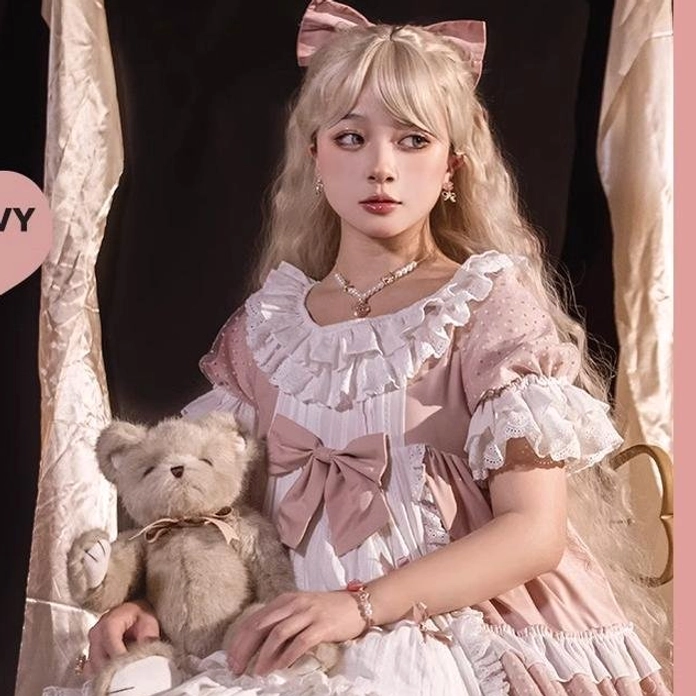 Model wearing blonde waltz lolita long curly wig pink bow half-body frontal shot