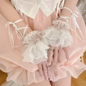 Close-up top view of white ruffled lace ballet arm cuffs worn on model's hands, paired with pink tulle skirt and white cropped shirt, showing delicate multi-layered lace details and adjustable satin tie straps in sweet lolita fashion styling