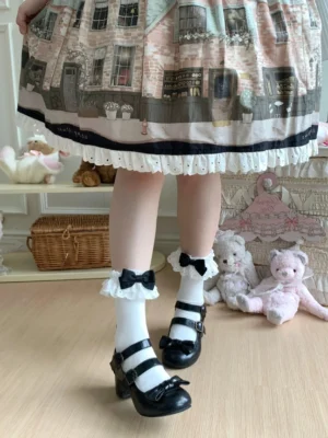 White lolita calf socks with black bow featuring double-layer lace trim worn with vintage print lolita skirt and black mary jane shoes on model in cozy indoor vintage room setting with plush toys