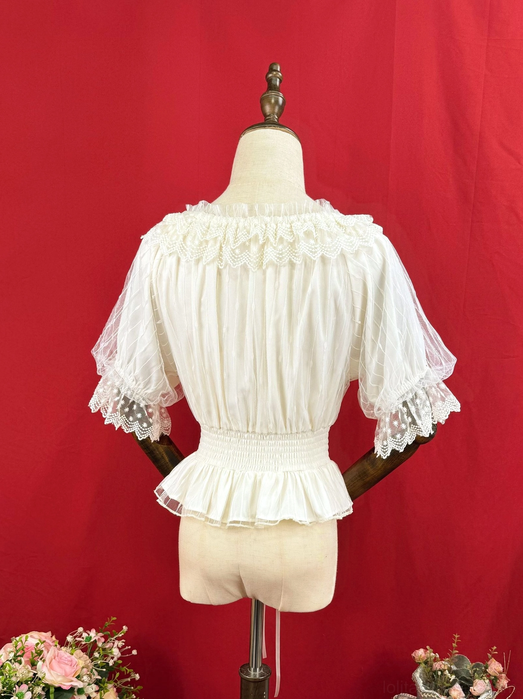 Rear perspective of white classic Lolita short-sleeve blouse displaying pleated chiffon bodice, adjustable shirred waist, ruffled hem and lace-edged mesh sleeves