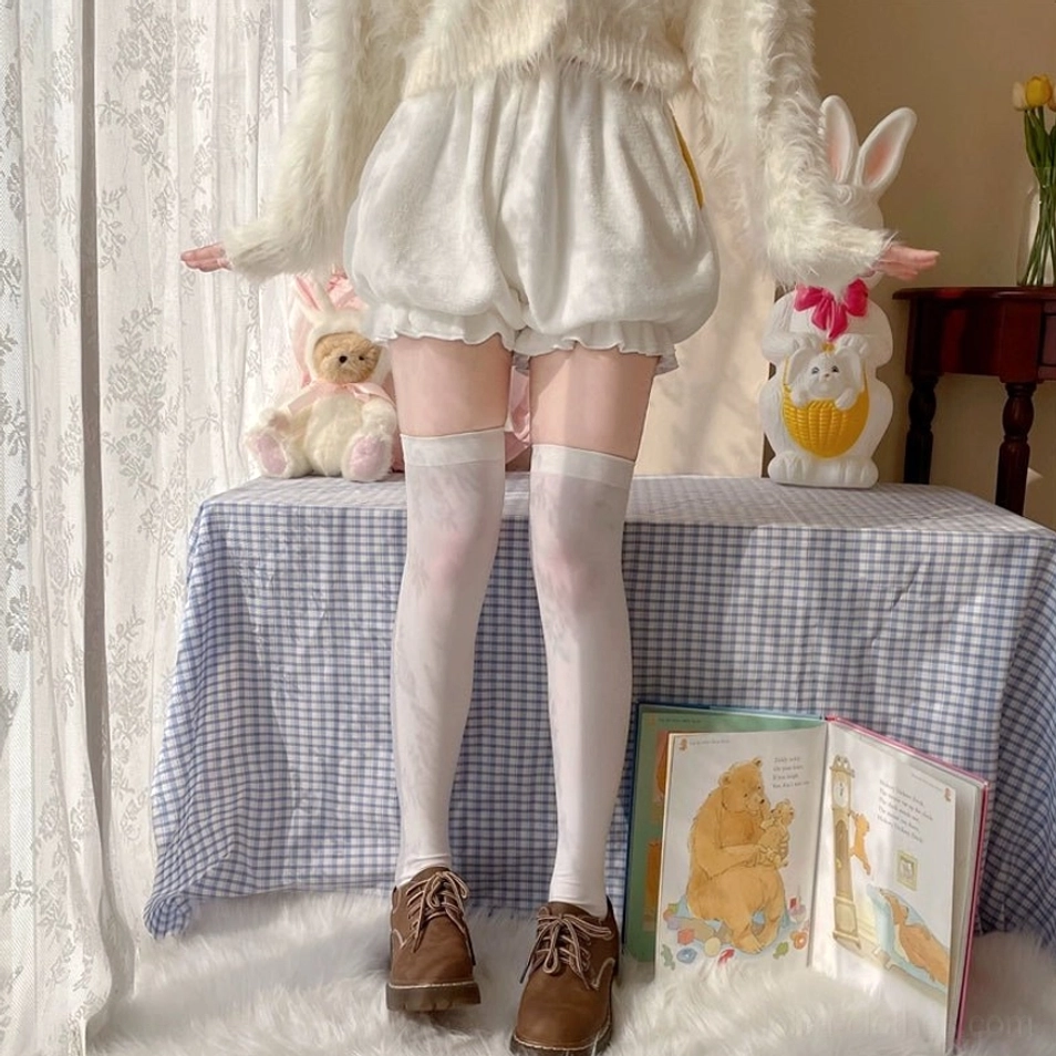 Full-body front coordinate view of white corgi-tail velvet Lolita bloomers styled with fuzzy white sweater thigh-high socks and brown loafers in cozy vintage home setting