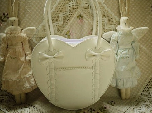 Cream white off-white heart-shaped Lolita tote bag front view with cream bow accents and angel doll props