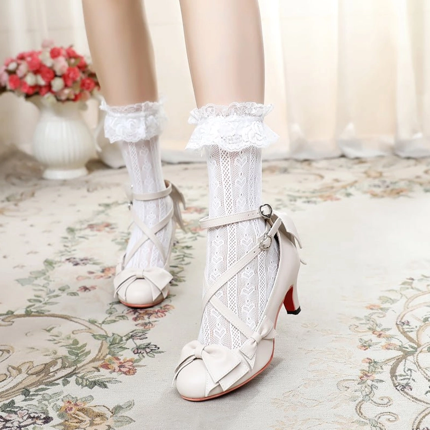 Off-white cross-strap sweet Lolita Mary Jane heels with red high heel worn with white lace frilly ankle socks, side-front view showing crisscross vamp straps and bow ornament on toe cap