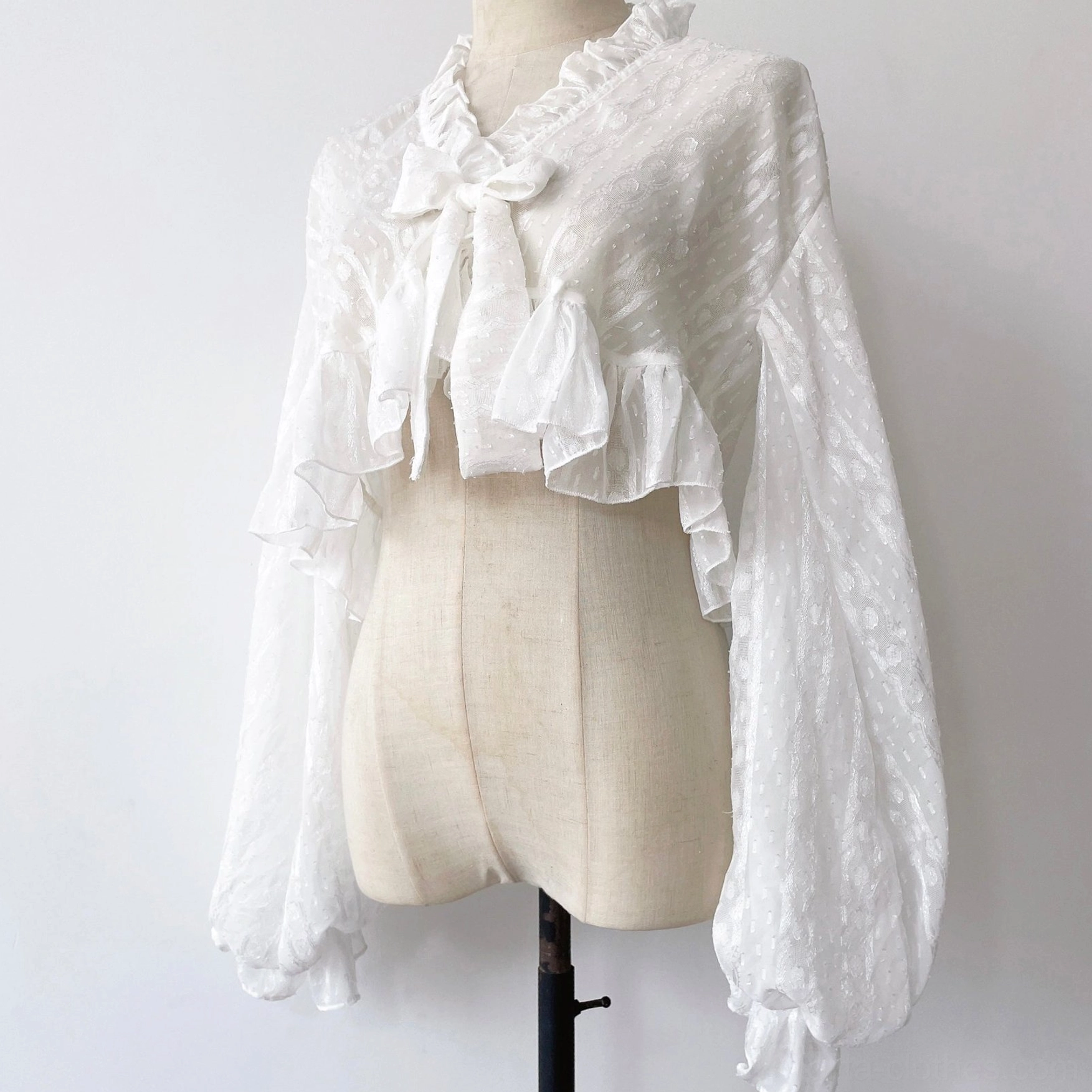 Pure white ruffled chiffon puff sleeve sweet Lolita cropped cardigan with stand collar and bow on dress form
