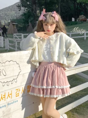 White fluffy puff sleeve sweet lolita cropped cardigan with doll collar and pearl buttons worn with pink ruffled skirt outdoor ranch scene half-body front view