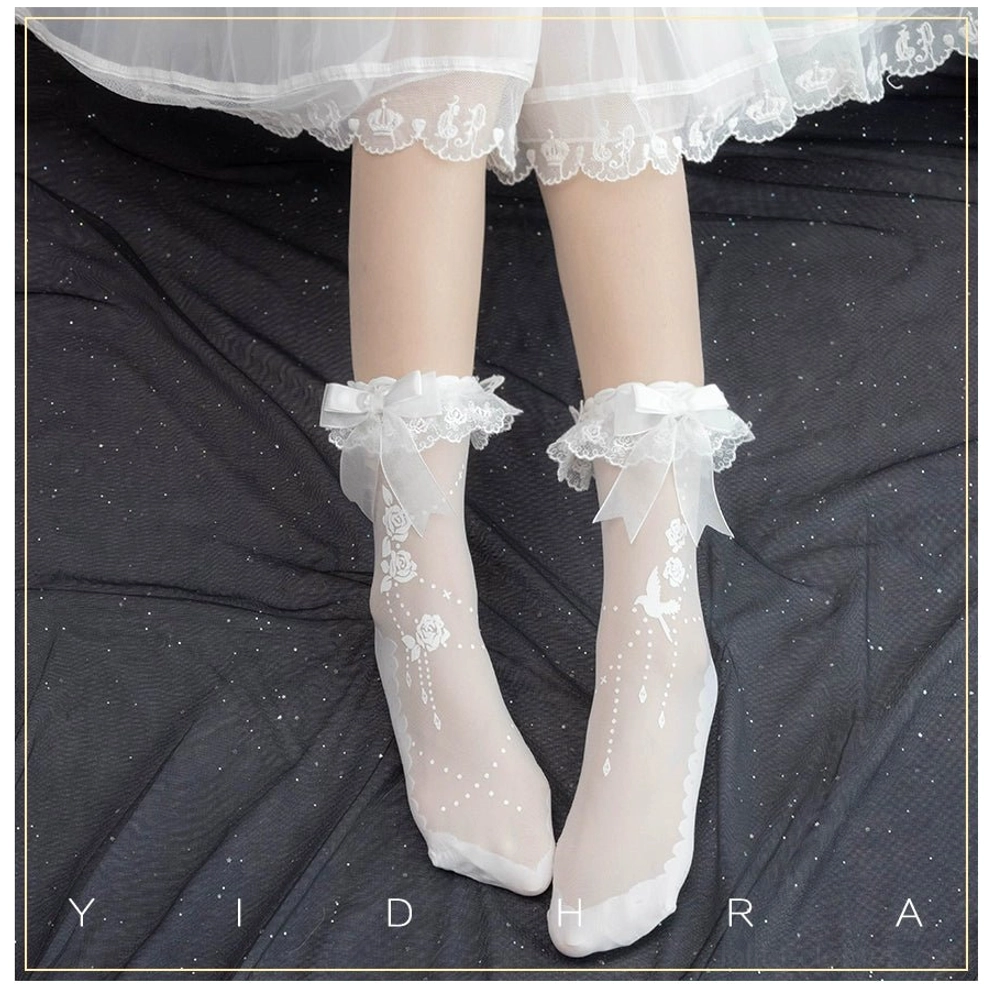 White Gothic Lolita ankle socks with rose and bird embroidery worn with white lace frilly skirt hem and sheer fabric details on dark sparkly backdrop