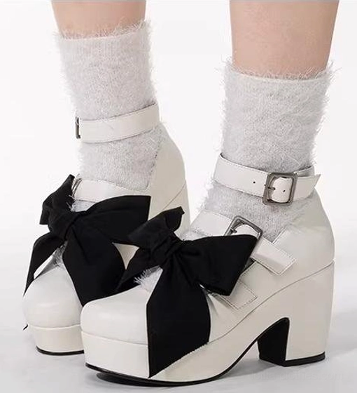 White Gothic Lolita platform heel shoes with large detachable black bow, single silver buckle ankle strap, chunky block heel, fluffy off-white crew socks, close-up front view model feet