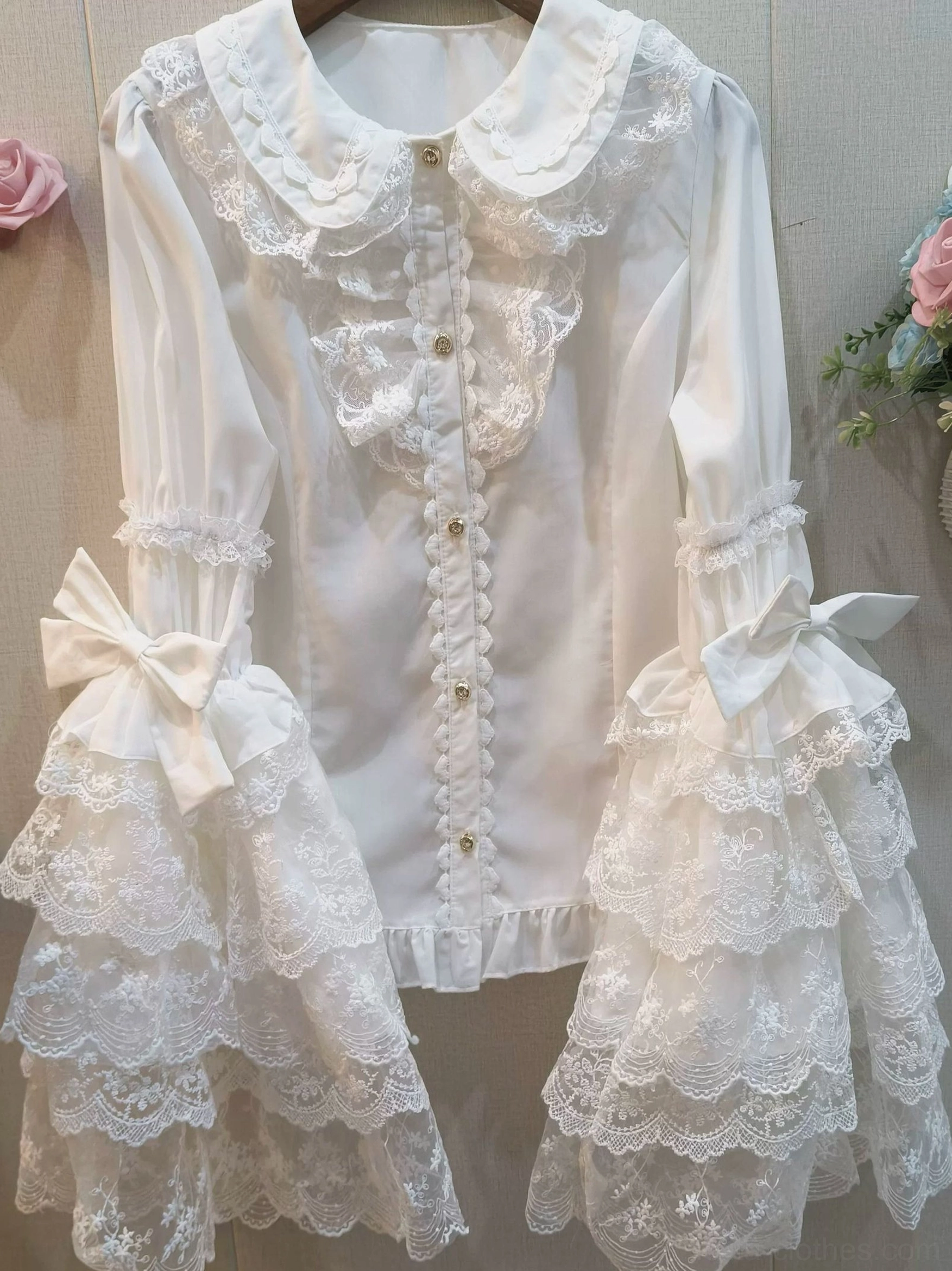White hime sleeve sweet lolita blouse with peter pan collar and heart-shaped lace trim, front flat view on hanger with floral background