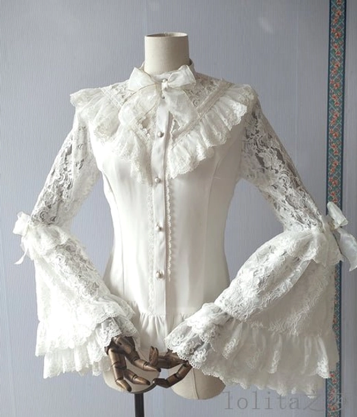 White elegant Lolita hime sleeve blouse with ruffled stand collar, detachable satin bow tie, pearl front buttons, floral lace trumpet sleeves with ruffled cuffs, and side bow decorations displayed on dress form front view