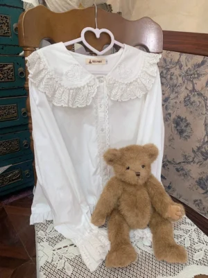 white sweet lolita long-sleeve cotton blouse with ruffled lace collar hung on heart-shaped hanger vintage chair teddy bear