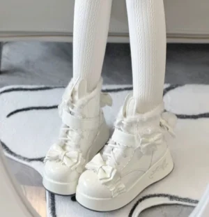 White kawaii lolita platform snow boots with bunny ear details and fluffy collar worn on feet with white ribbed stockings indoor home setting