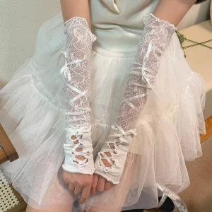 White hollow lace Lolita arm sleeves with cross satin ribbon decoration and fingerless cutout wrist design worn by model in light tulle dress