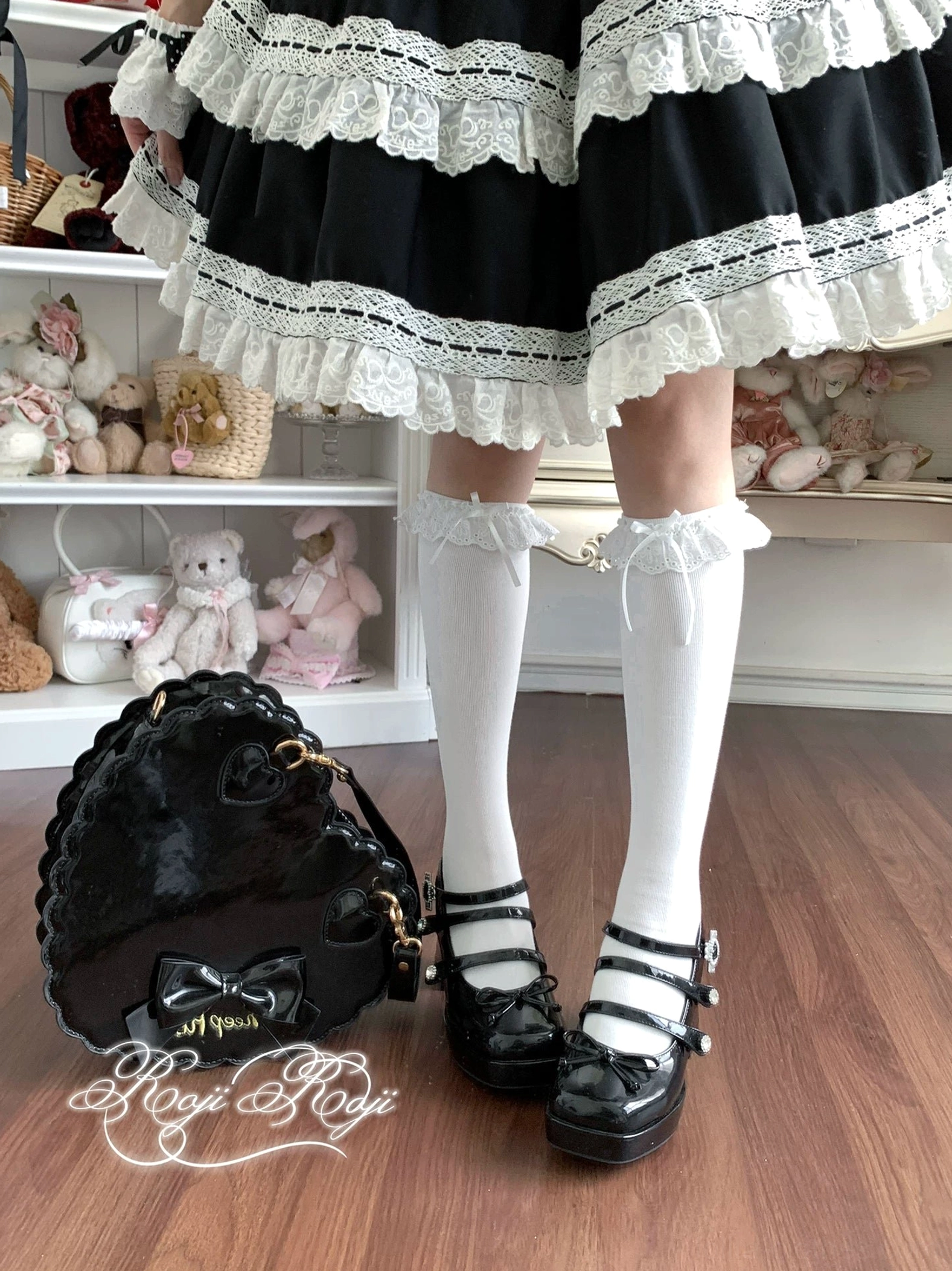 Pure white lace-trimmed sweet lolita mid-calf socks with ruffled cuff and bow accents, worn with black platform Mary Jane shoes and black-white frilly lolita dress, front overhead full lower-body view