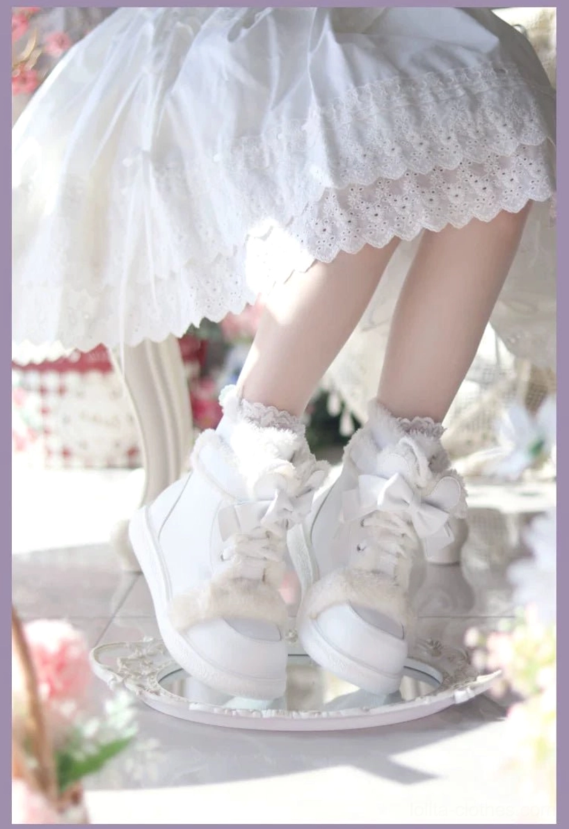 White lolita winter boots with plush cuff and bow lace details on overhead flat lay display with floral decorative props
