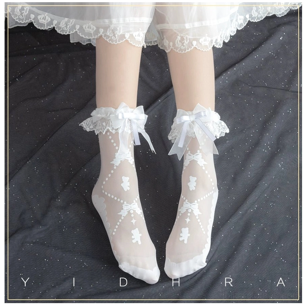 White lolita ankle socks featuring ruffled lace bow cuff and printed bear with bow jacquard details on sheer fabric under lace skirt