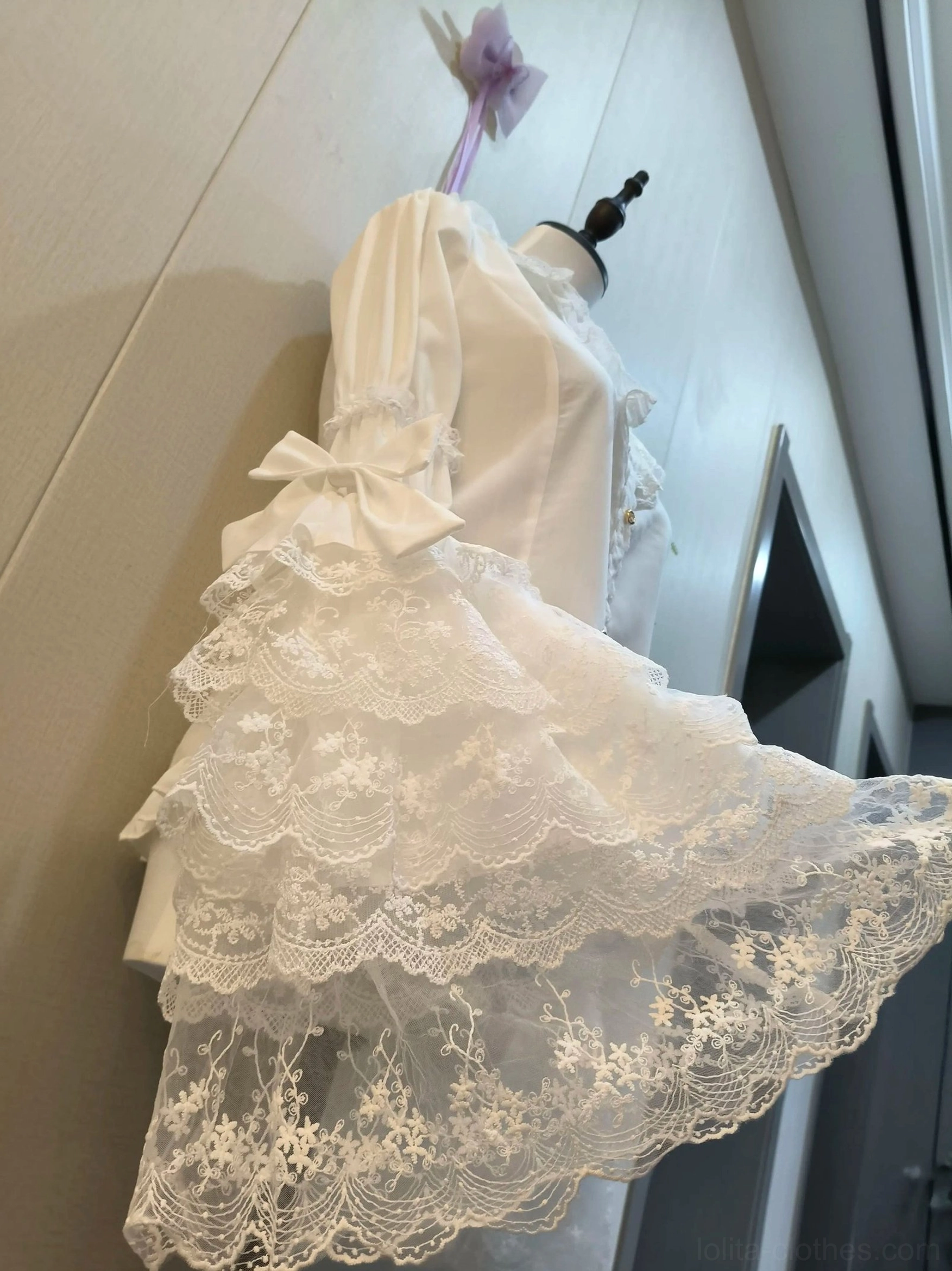 Rear side view of white sweet lolita blouse, showing hime sleeve with satin bow and embroidered lace pattern on tailored silhouette