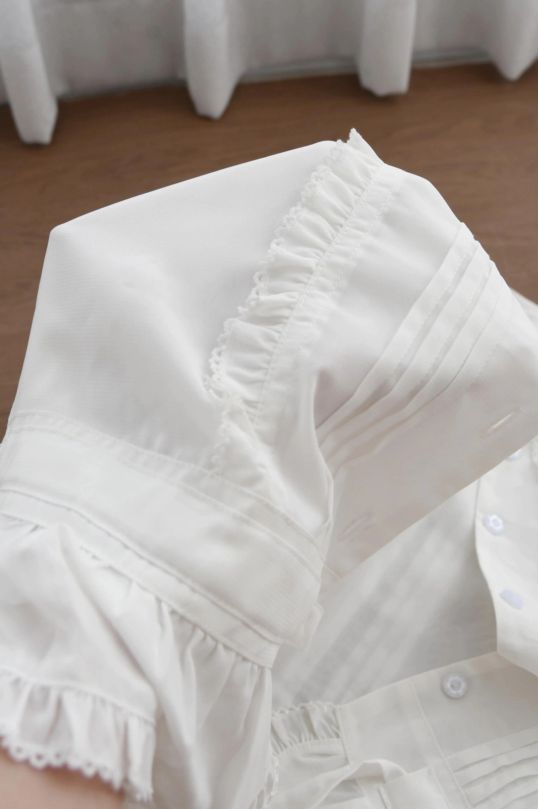 Close-up detail of white double-layered chiffon sweet Lolita blouse showing ruffled collar edge, hidden button closure, and neat tailoring stitches