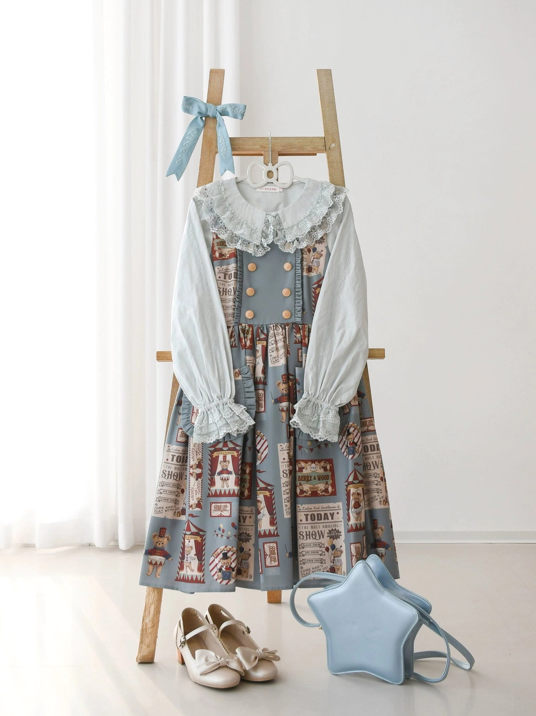 Full body mannequin wearing white Lolita blouse with vintage town print JSK dress featuring double-breasted front decor, lace ruffled collar and cuffs, styled with wooden ladder, blue handbag and flat shoes