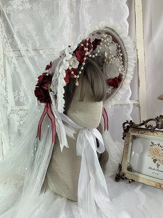 White lolita bonnet rear three quarter view white lace trim red and white floral arrangements pearl chains ribbon