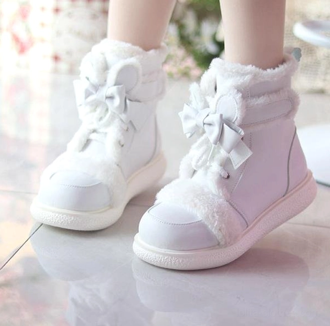 White lolita winter ankle boots close-up side-front view showing thick plush boot cuff, satin bow accent, and low-profile rubber outsole on glossy studio floor