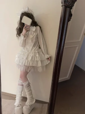 Full-length mirror selfie of white lolita bubble puff sleeve blouse with tiered ruffle tulle skirt, cat ear headband, curly hair, ruffled knee-high socks and platform loafers