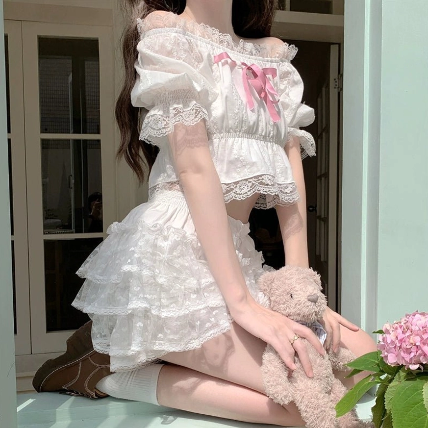 White Lolita lace bloomer set with shirred elastic waist, layered ruffled shorts and delicate lace trim worn by kneeling model on indoor windowsill with pink hydrangea flowers