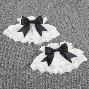 Sweet lolita wrist cuffs white pair flat lay with scalloped lace trim and black satin bow ornament overhead view