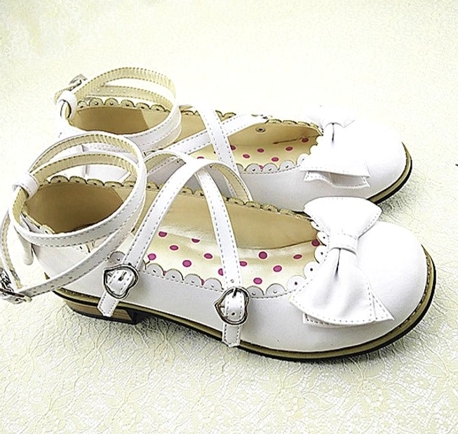 White sweet Lolita low heel princess shoes with cross buckled ankle straps, white bow vamp decoration, and polka dot inner lining, flat lay top view on light background