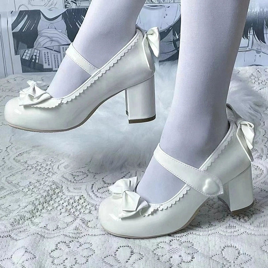 White Lolita Mary Jane block high heel shoes with scalloped lace trim front bow and heart-shaped strap buckle on feet with sheer white stockings displayed on embroidered lace fabric