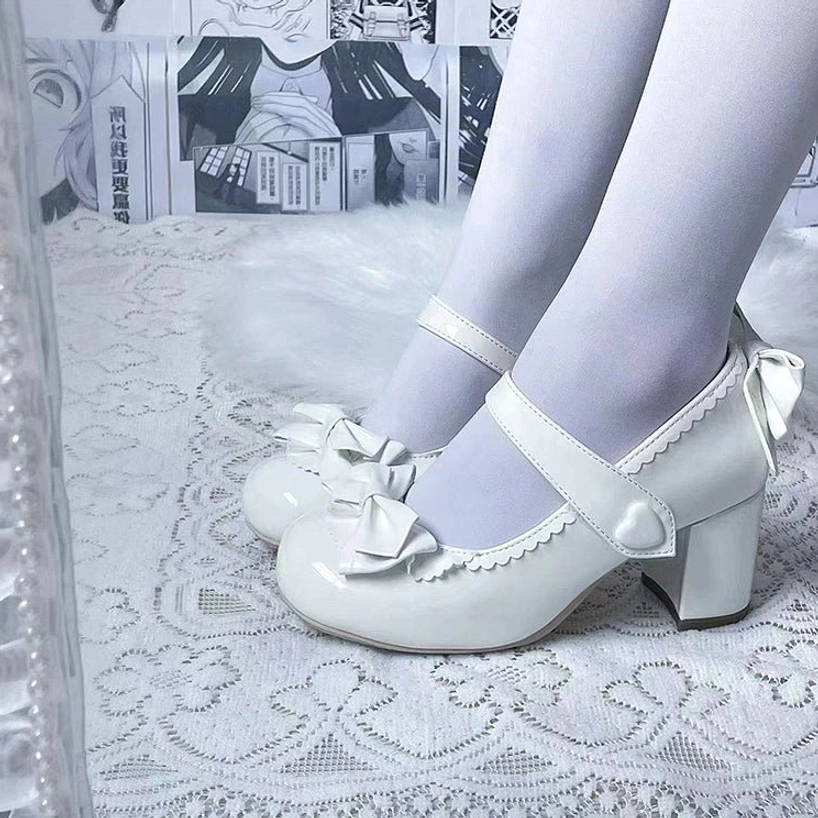 White Lolita Mary Jane block high heel shoes with toe-cap bow scalloped trim heart strap buckle and patent leather surface top-down close-up of both feet wearing shoes