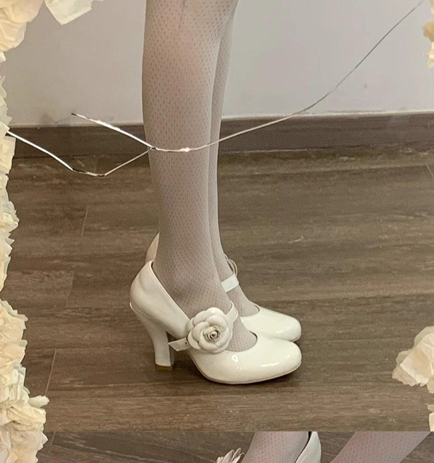 White Lolita Mary Jane high heels with rose decor side view of both wearing feet indoor wooden floor fairy lights ruffled trim block heel classic Mary Jane strap sheer dotted stockings
