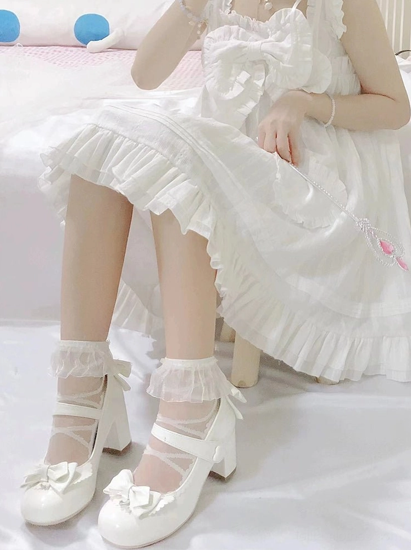 White Lolita Mary Jane low-heel shoes with toe-cap bow on girl wearing frilly white Lolita dress with lace frill socks partial side body shot