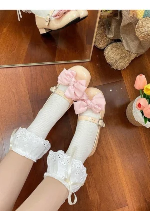 White lolita mid-calf socks with delicate lace trim and removable pink bow accent, top-down close-up shot on wooden floor with plush toys