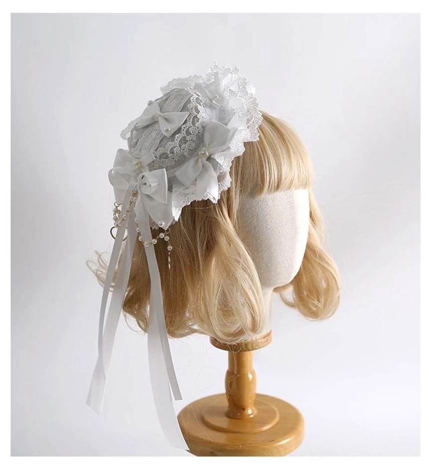 Pure white classic lolita mini side hair hat with ruffled lace, satin bow, pearl tassel ribbons, left three-quarter view on mannequin